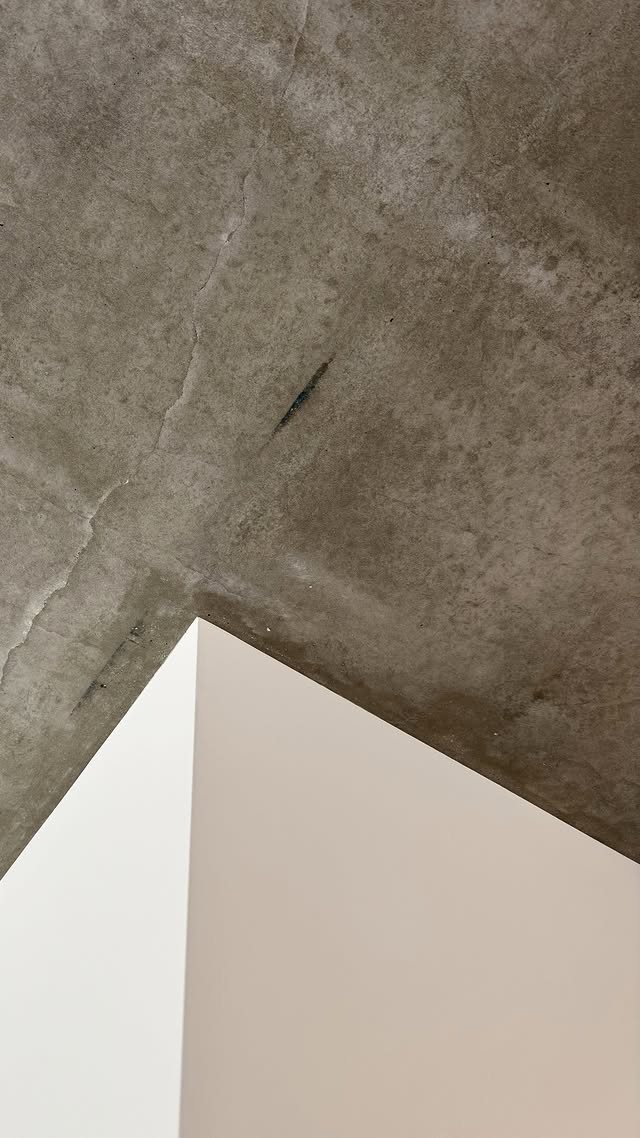 Precyzyjny styk białej ściany z surowym betonowym sufitem